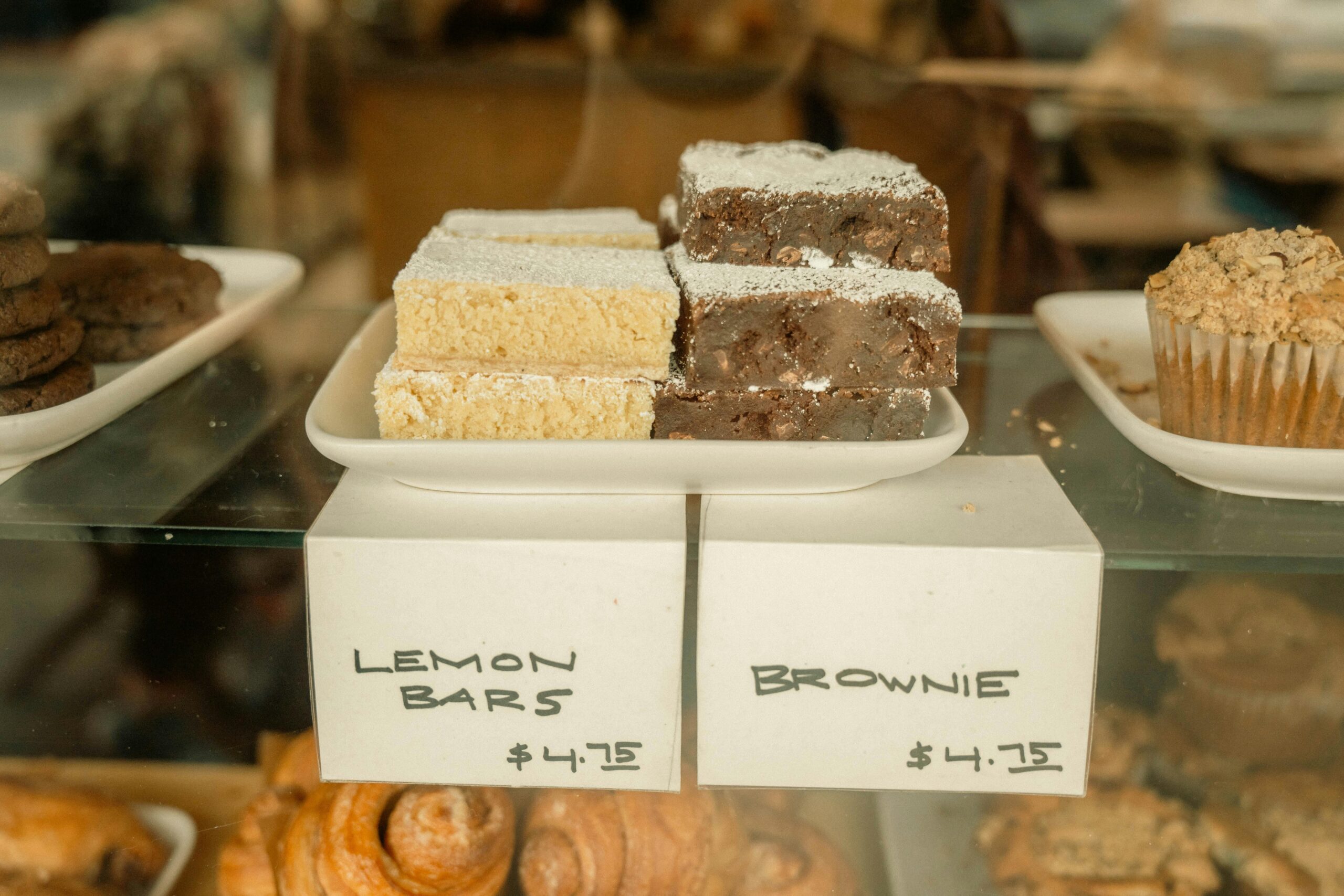 Delicious display of lemon bars and brownies in a bakery with price tags.